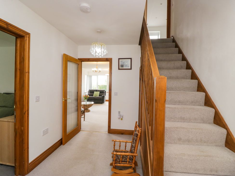 A hallway with a staircase and a chair at Sherriff in Troutbeck, near Keswick