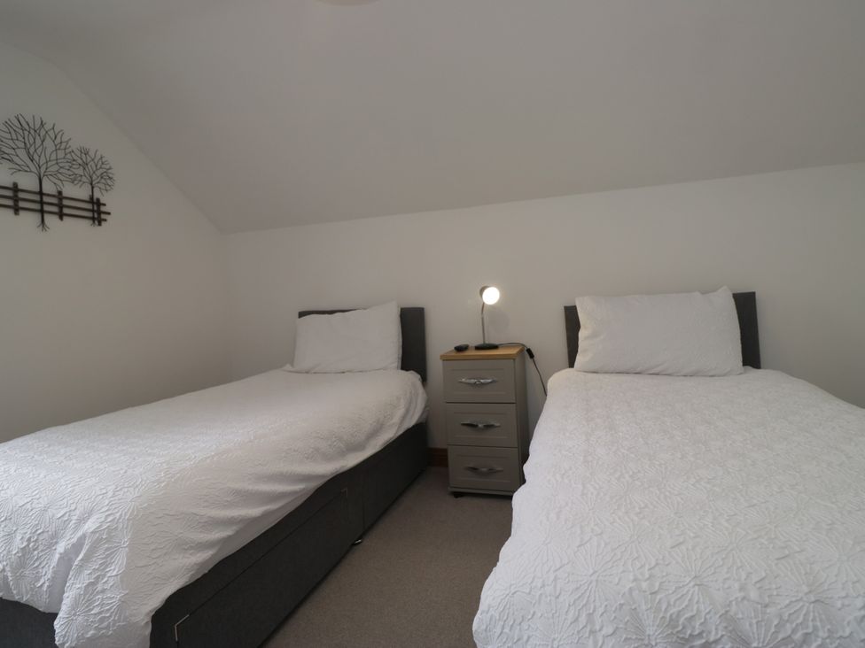 A bedroom with two single beds and a nightstand at Sherriff in Troutbeck, near Keswick
