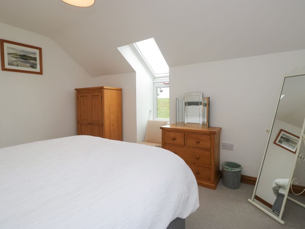A bedroom with a bed, wooden cabinet, and mirror at Sherriff in Troutbeck, near Keswick