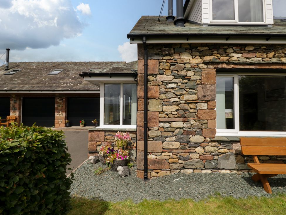 An outdoor view of a stone wall with plants and a bench at Sherriff, Troutbeck, near Keswick