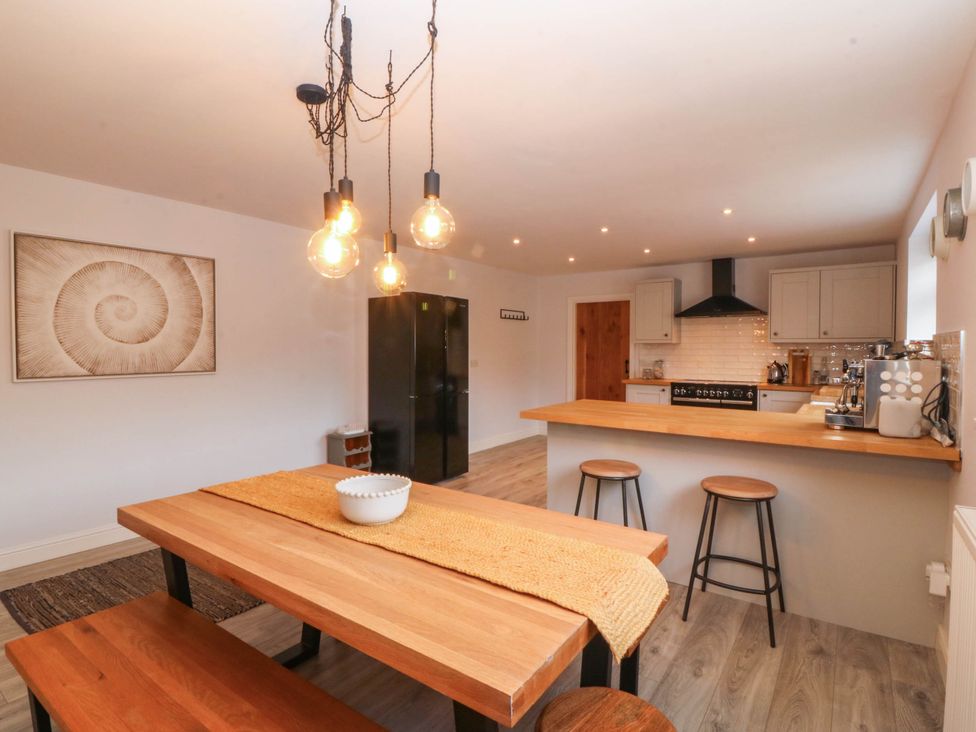 A kitchen with a dining table and chairs at Afallon in Llanbedrog