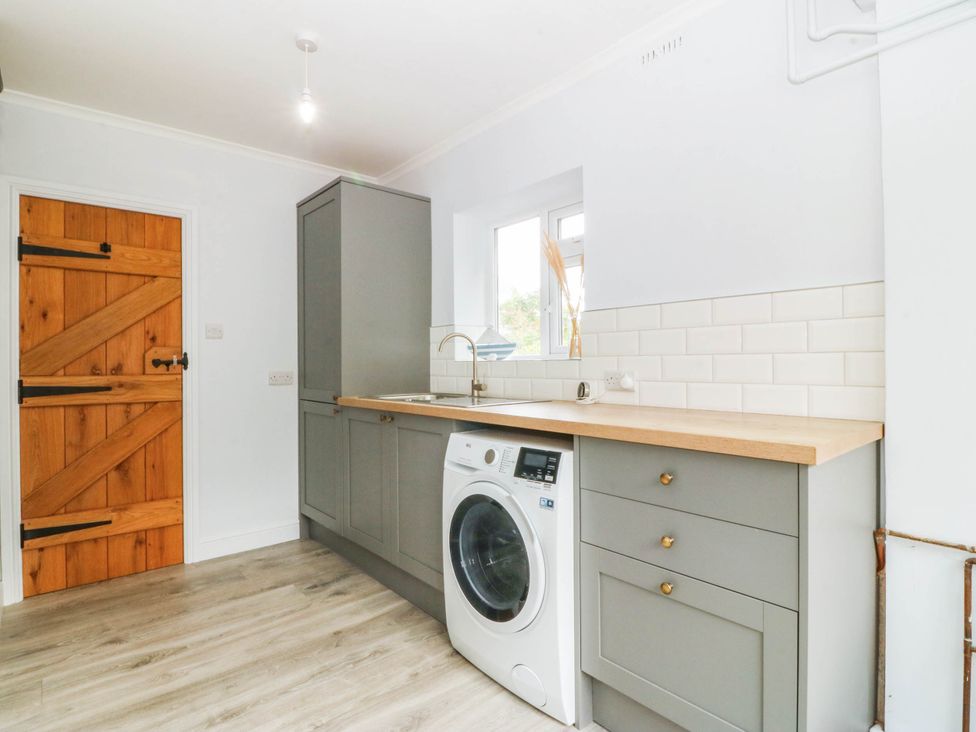 A laundry room with a washing machine and sink at Afallon Llanbedrog
