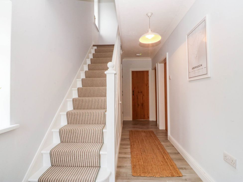 A hallway with a staircase and a door at Afallon in Llanbedrog