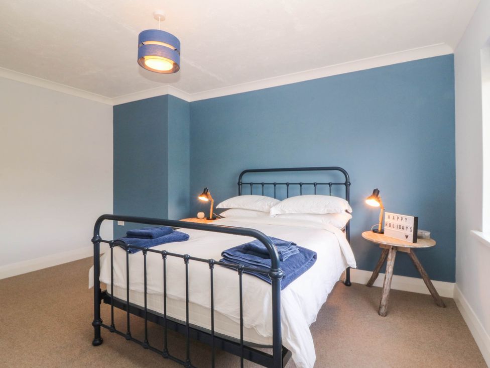 A bedroom with a bed and a decorative sign at Afallon in Llanbedrog
