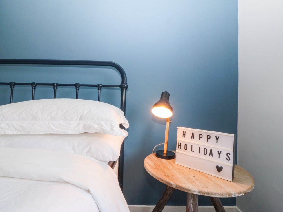 A bedroom with a bed and a lamp at Afallon Llanbedrog