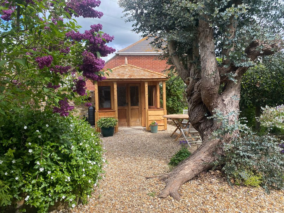 A wooden structure and dining table in a garden at Little Brook in Nottington near Weymouth