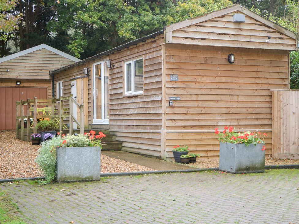 A wooden cabin exterior with decking and planters at Orchard Lodge in Bolney