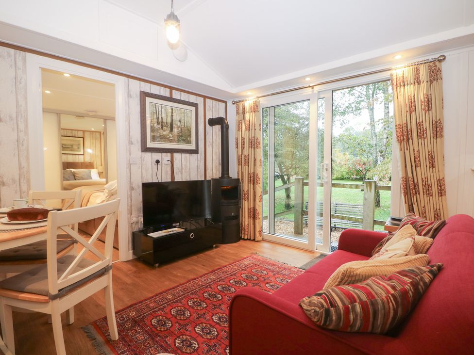 A living room with a television and sofa at Orchard Lodge in Bolney