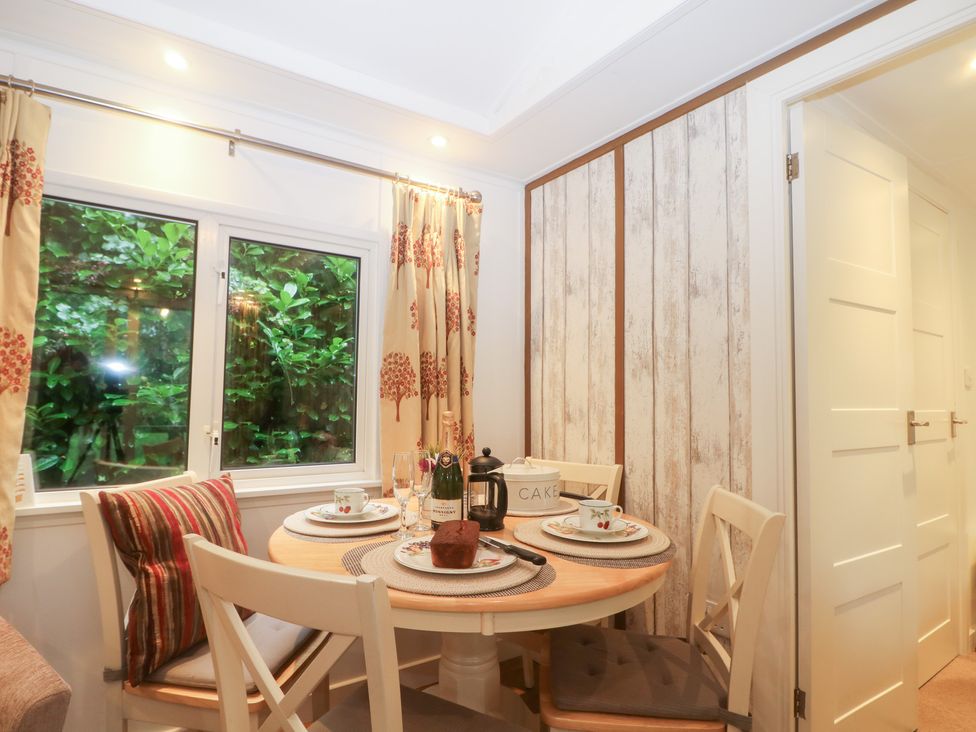 A dining room with a round table and chairs at Orchard Lodge in Bolney