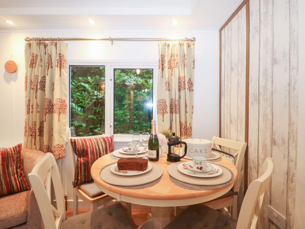 A dining area with a round table set for a meal at Orchard Lodge in Bolney