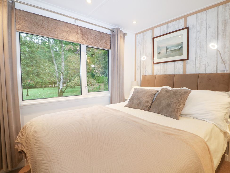 A bedroom with a bed and window at Orchard Lodge in Bolney
