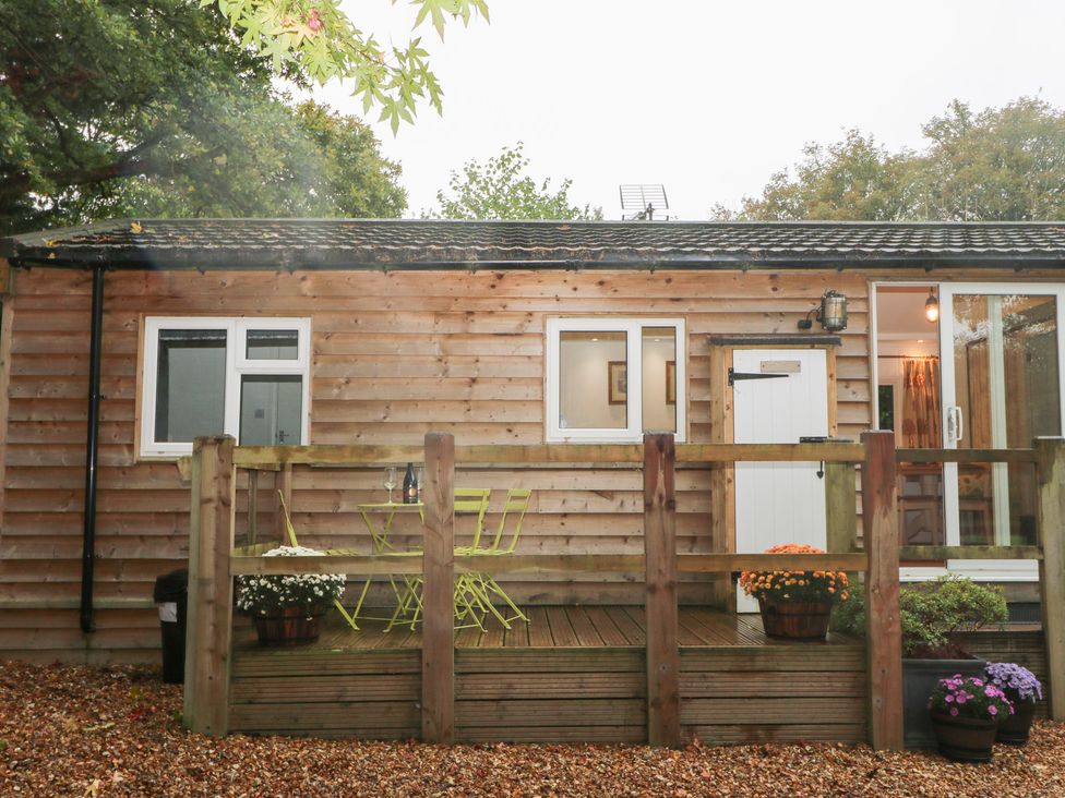 A wooden deck with a table and chairs at Orchard Lodge in Bolney