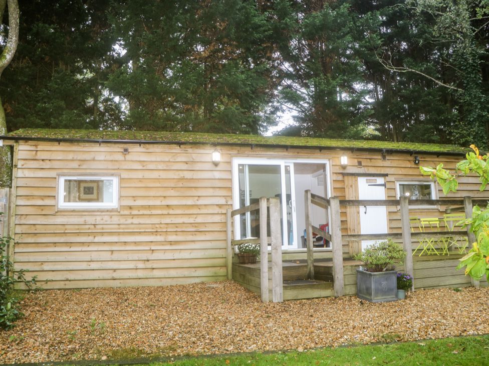 A wooden cabin with a porch and sliding door at Harvest Lodge in Wineham near Bolney