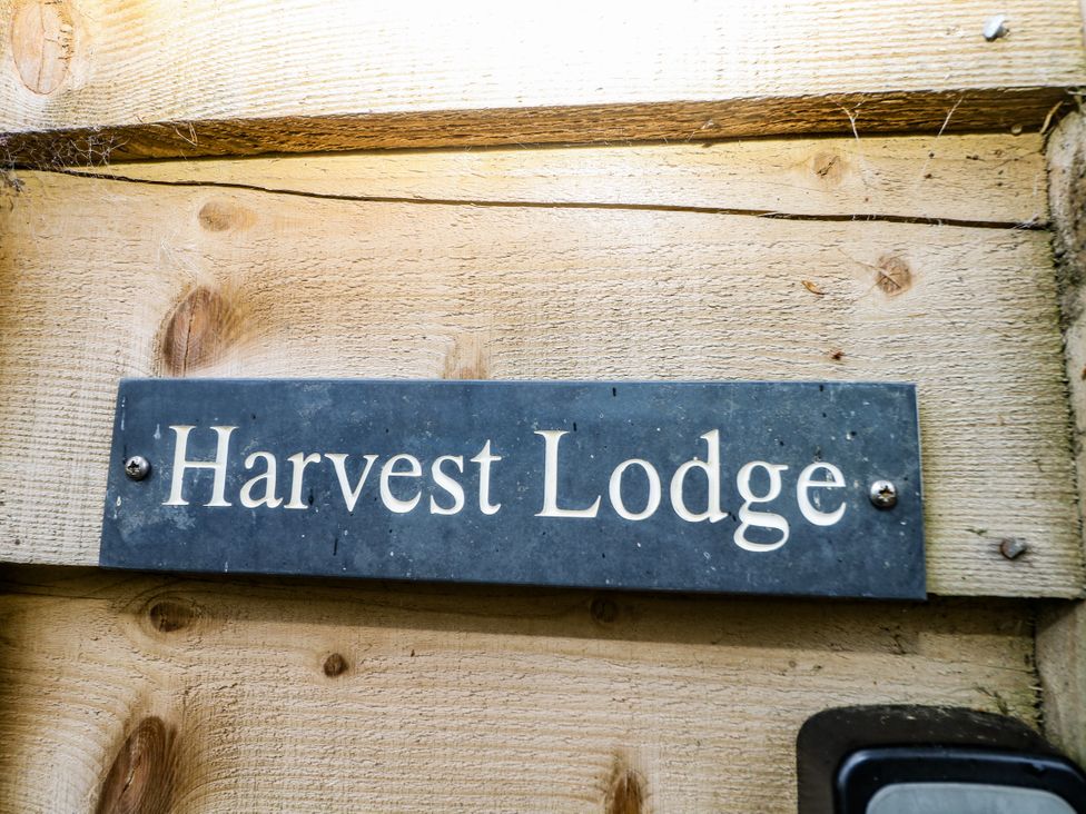 A sign of Harvest Lodge on wooden surface in Wineham near Bolney