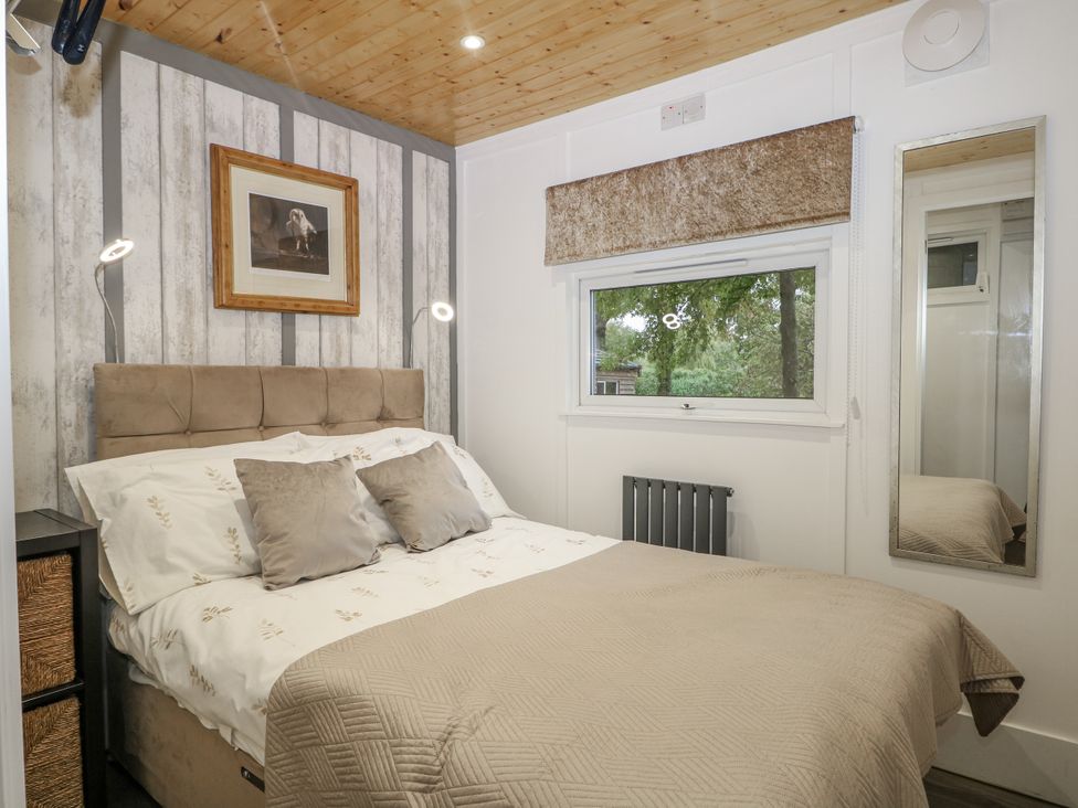 A bedroom with a bed and wooden walls at Harvest Lodge in Wineham near Bolney