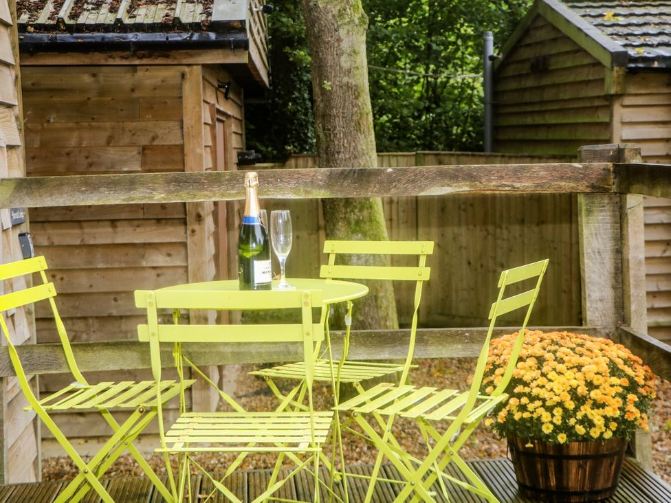 A table with chairs and a champagne bottle at Harvest Lodge in Wineham near Bolney