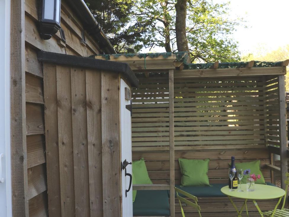 An outdoor seating area with cushions and a table at Harvest Lodge in Wineham near Bolney