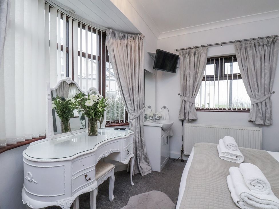 A bedroom with a vanity and fresh flowers at Beachcrest in Whitby
