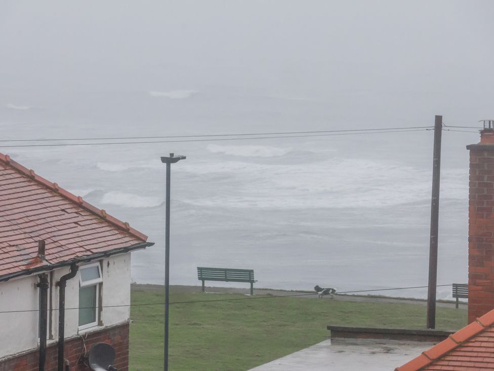 View of ocean and grassy area with a bench at Beachcrest in Whitby