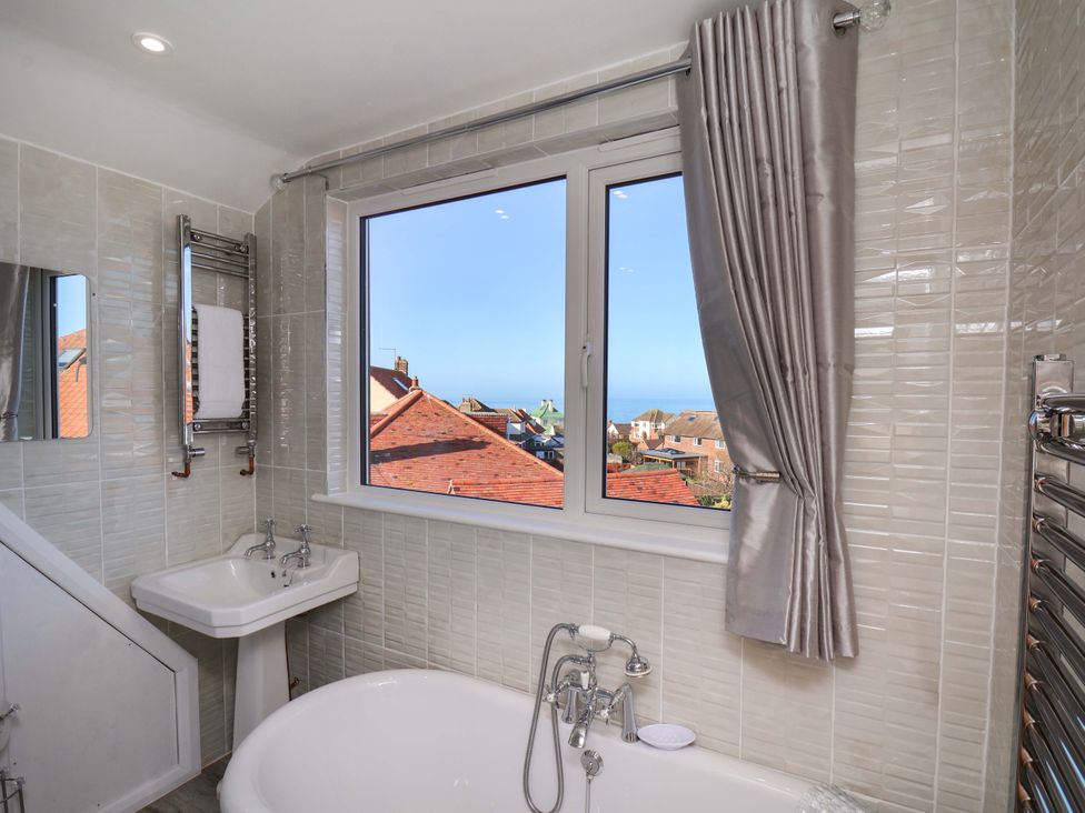 A bathroom with a bathtub, sink, and window view at Beachcrest in Whitby