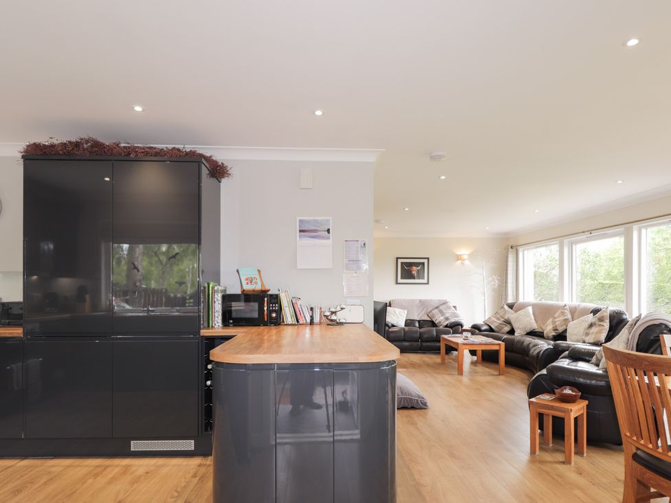 A kitchen and living area with a sofa and dining chairs at Culreach Lodge Grantown-on-Spey near Nethy Bridge