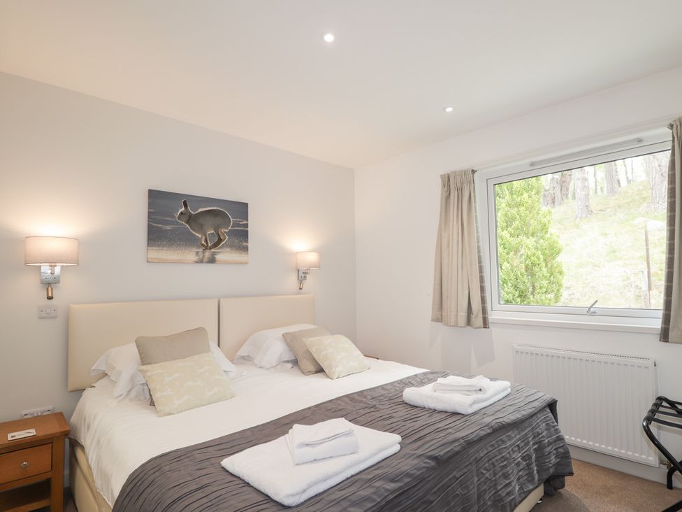 A bedroom with a double bed and artwork at Culreach Lodge in Grantown-on-Spey near Nethy Bridge