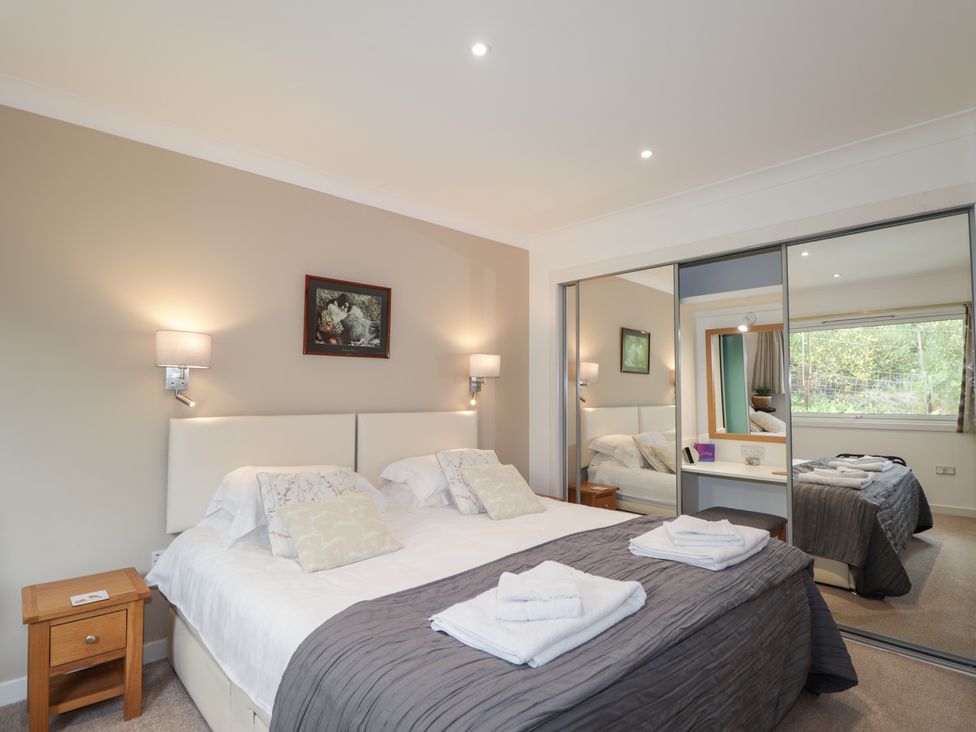 A bedroom with a bed and mirrored wardrobe at Culreach Lodge in Grantown-on-Spey near Nethy Bridge