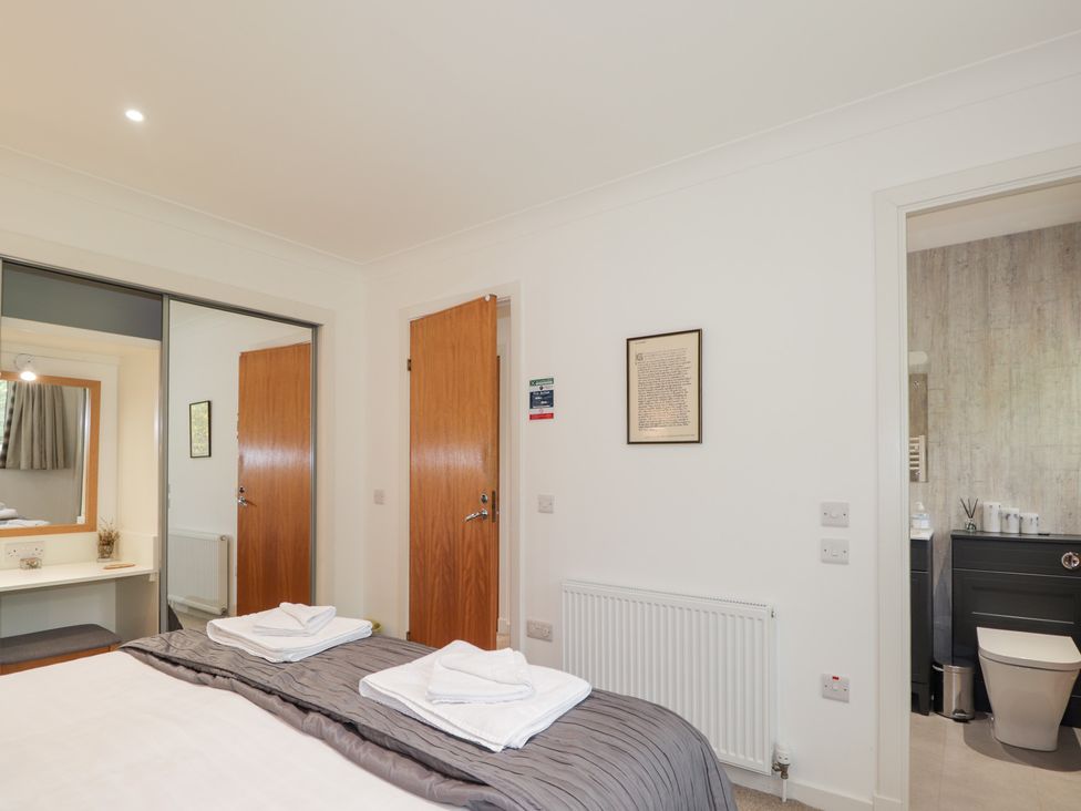 A bedroom with bed linens and a mirror at Culreach Lodge in Grantown-on-Spey near Nethy Bridge