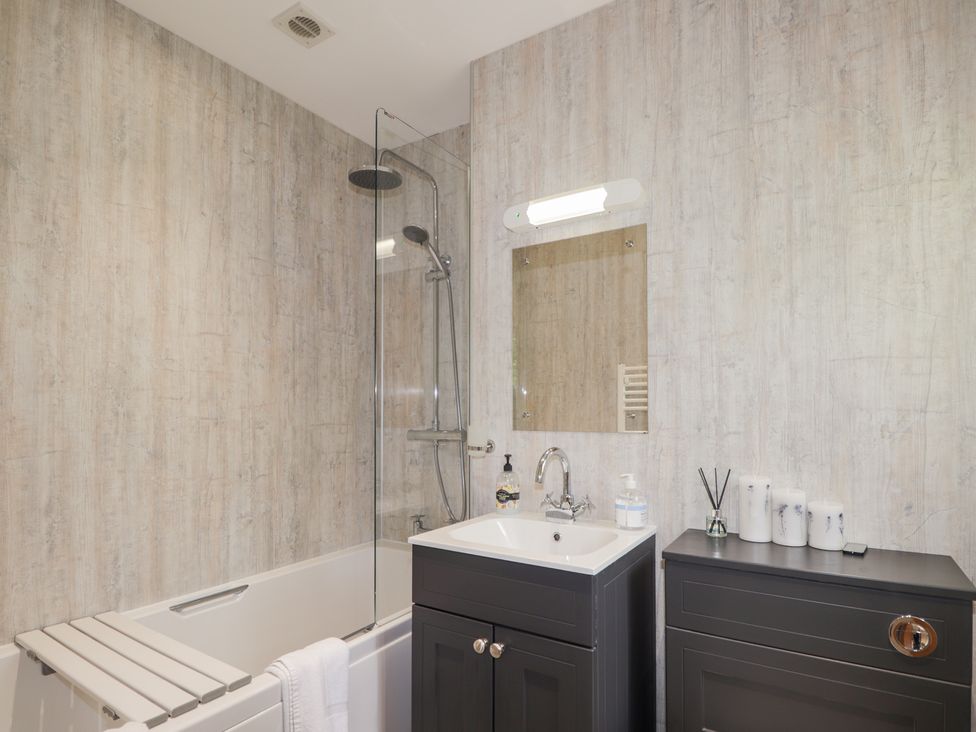 A bathroom with a bathtub, shower, and sink at Culreach Lodge in Grantown-on-Spey near Nethy Bridge