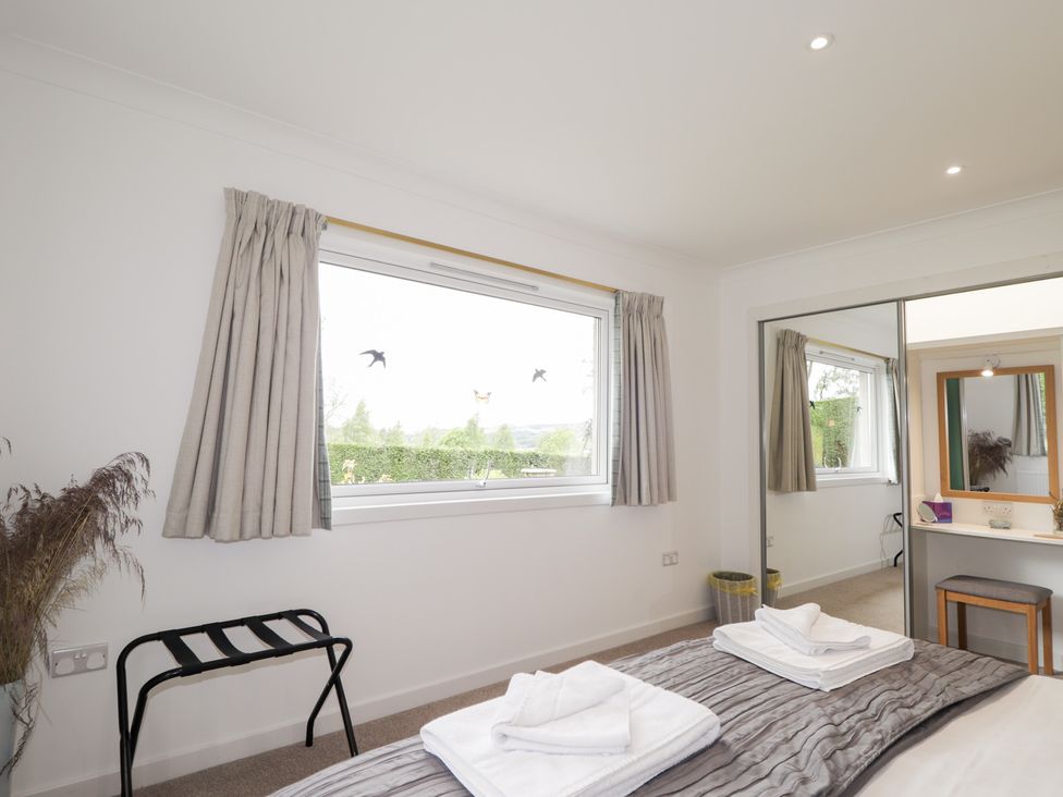 A bedroom with a bed and a mirror at Culreach Lodge in Grantown-on-Spey near Nethy Bridge