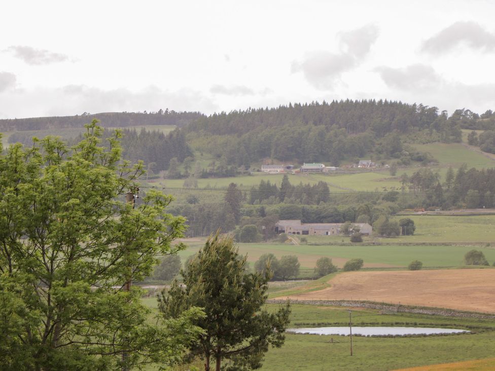 A landscape with trees, houses, and a pond at Culreach Lodge Grantown-on-Spey near Nethy Bridge