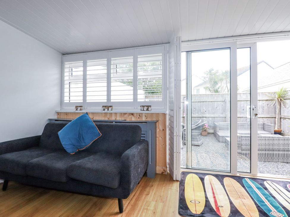 A snug with a couch and sliding door leading to outdoor area at The Three Tees in Newquay