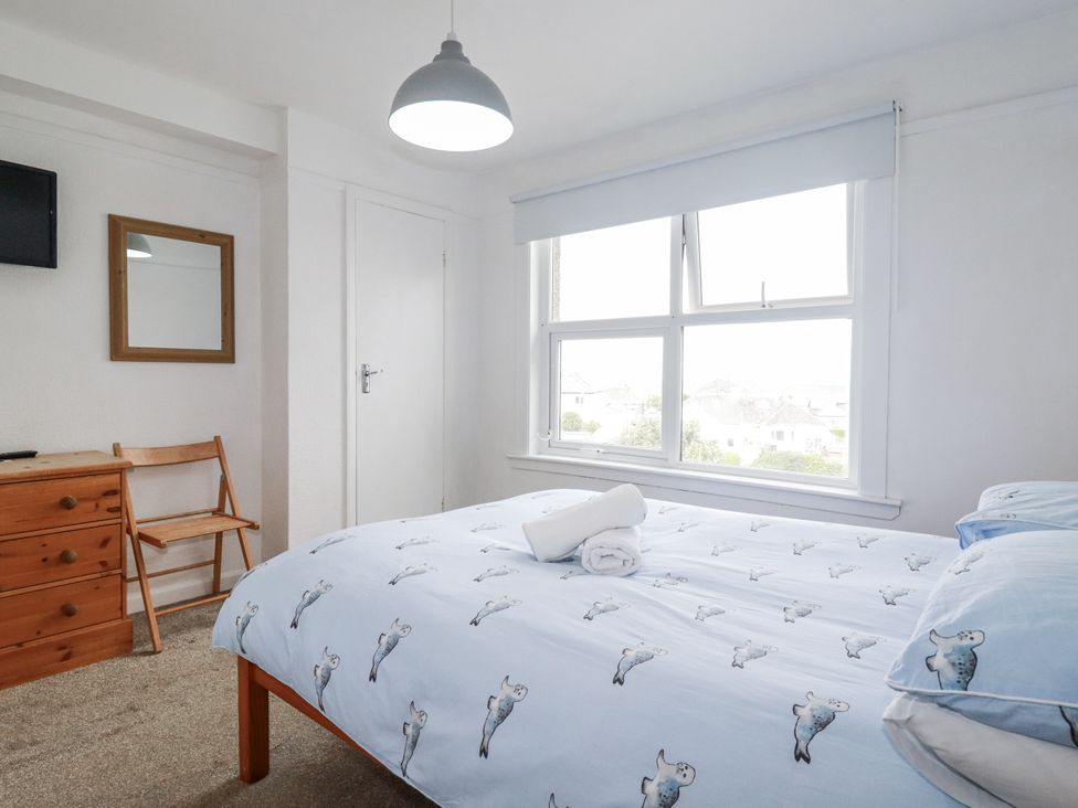 A bedroom with a bed and a chair at The Three Tees in Newquay