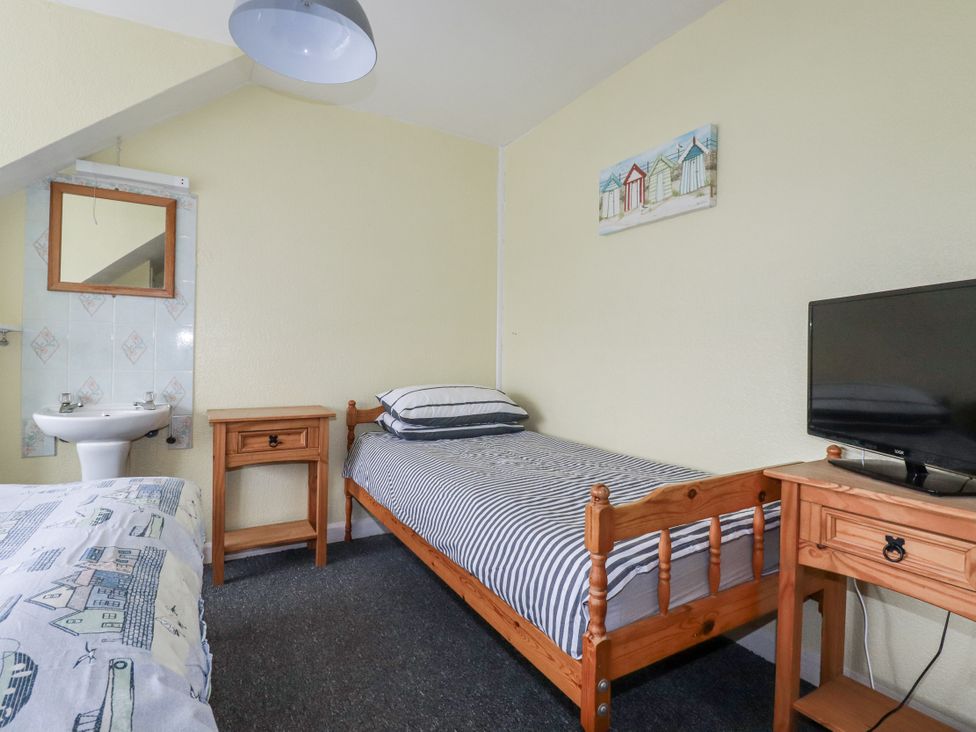 A bedroom with a bed, sink and mirror at The Three Tees in Newquay