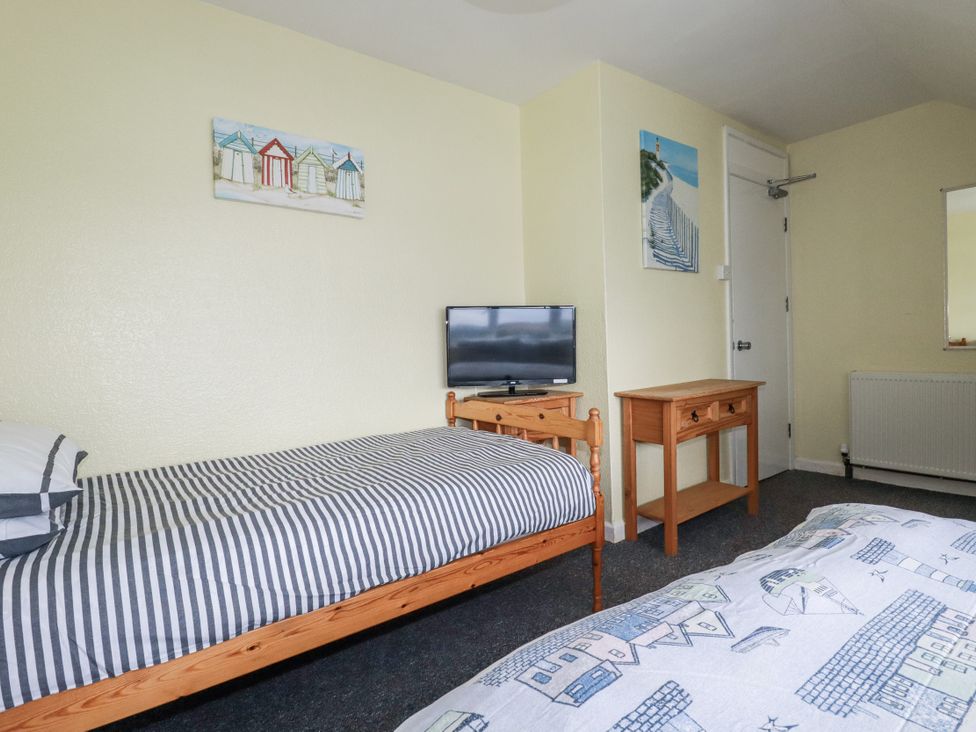 A bedroom with a single bed and a double bed and a television at The Three Tees in Newquay