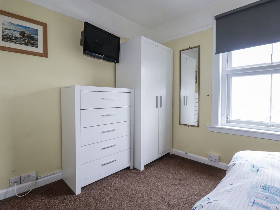 A bedroom with a bed, wardrobe, and television at The Three Tees in Newquay