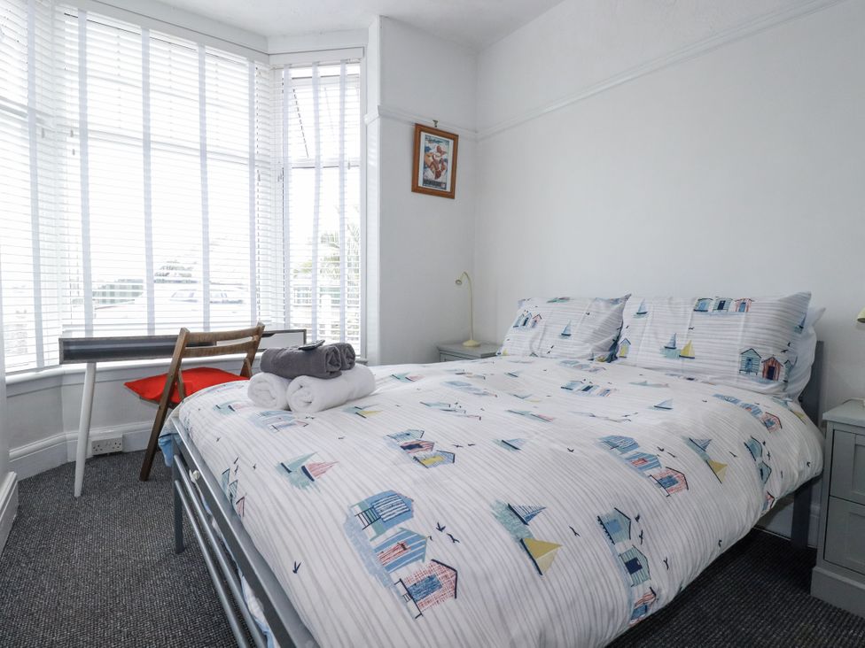 A bedroom with a bed, table, chair, and towel at The Three Tees in Newquay