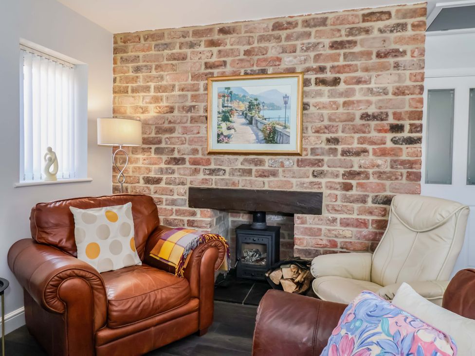A living room with a brick wall and fireplace at Southview Bungalow in Barmston