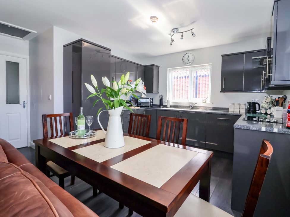 A kitchen with a dining table and flowers at Southview Bungalow in Barmston