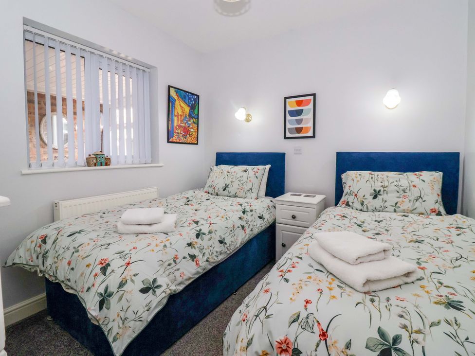 A bedroom with two single beds and a bedside table at Southview Bungalow in Barmston