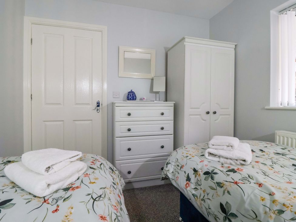 A bedroom with two beds, a wardrobe and a chest of drawers at Southview Bungalow in Barmston