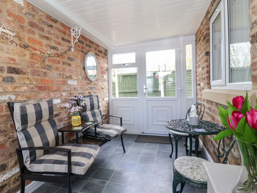 A conservatory with seating and plants at Southview Bungalow in Barmston