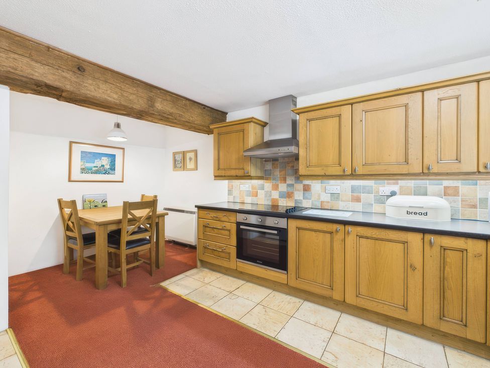 A kitchen with wooden cabinets and dining table at The Roundhouse in Warbstow