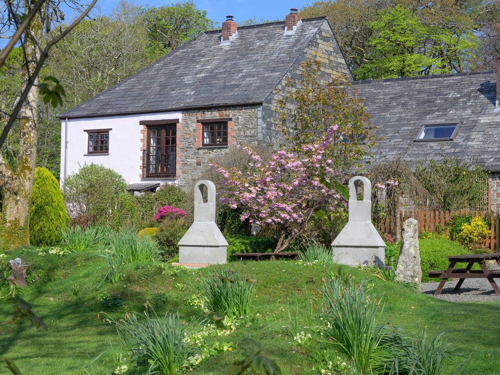 A garden with a house and flower trees at Beech Cottage in Warbstow