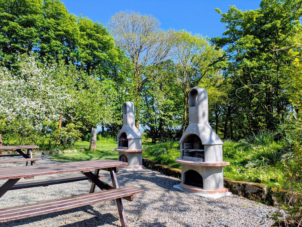 An outdoor area with two barbecues and picnic benches at Little Leighs in Warbstow