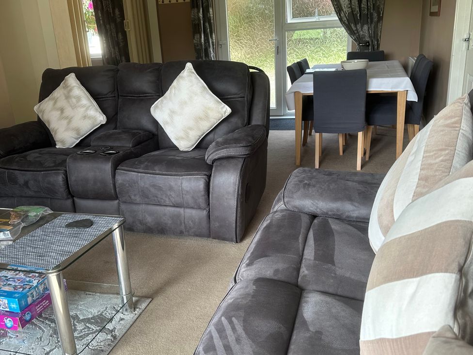 A living room with a sofa and dining area at Watergate Bay in Liskeard