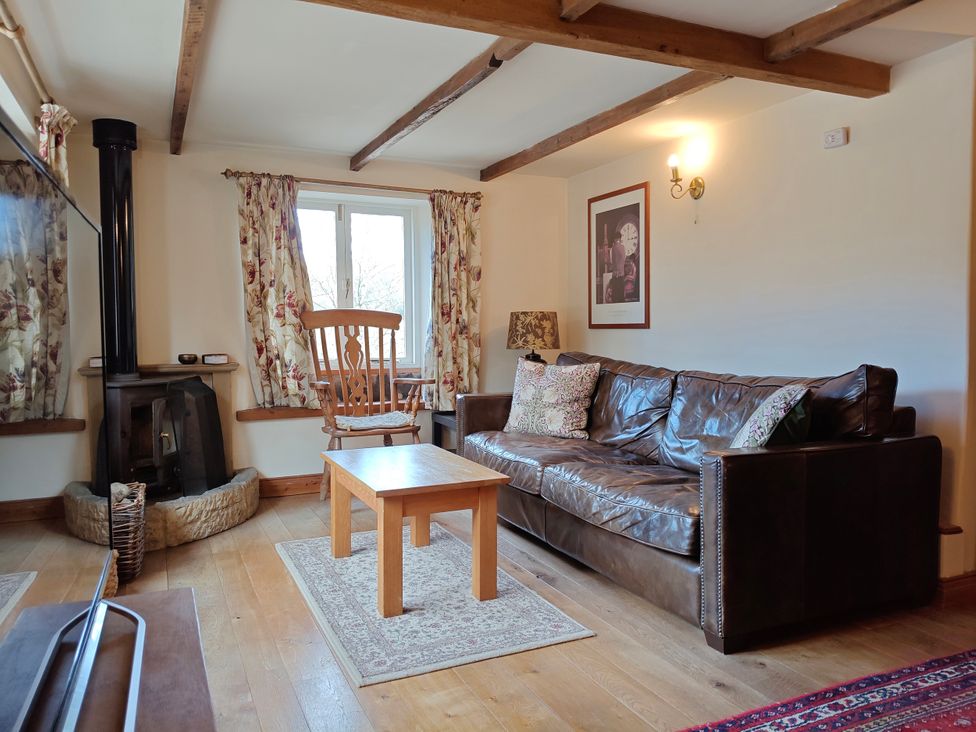 A living room with a sofa, coffee table, and stove at Green Farm Stables in Hognaston near Carsington Water