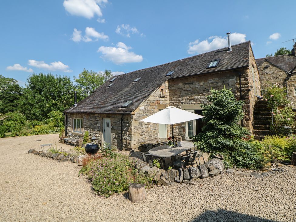 A cottage with table and chairs under an umbrella at Green Farm Stables in Hognaston near Carsington Water