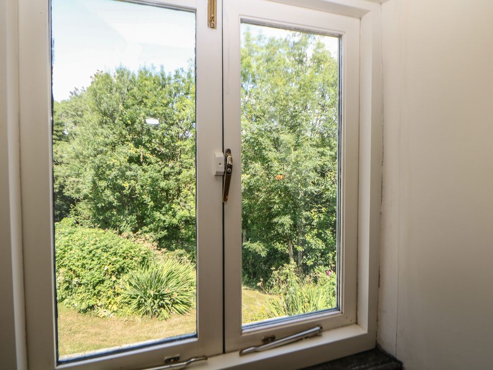 A window showing a garden with trees and bushes at Green Farm Stables Hognaston near Carsington Water
