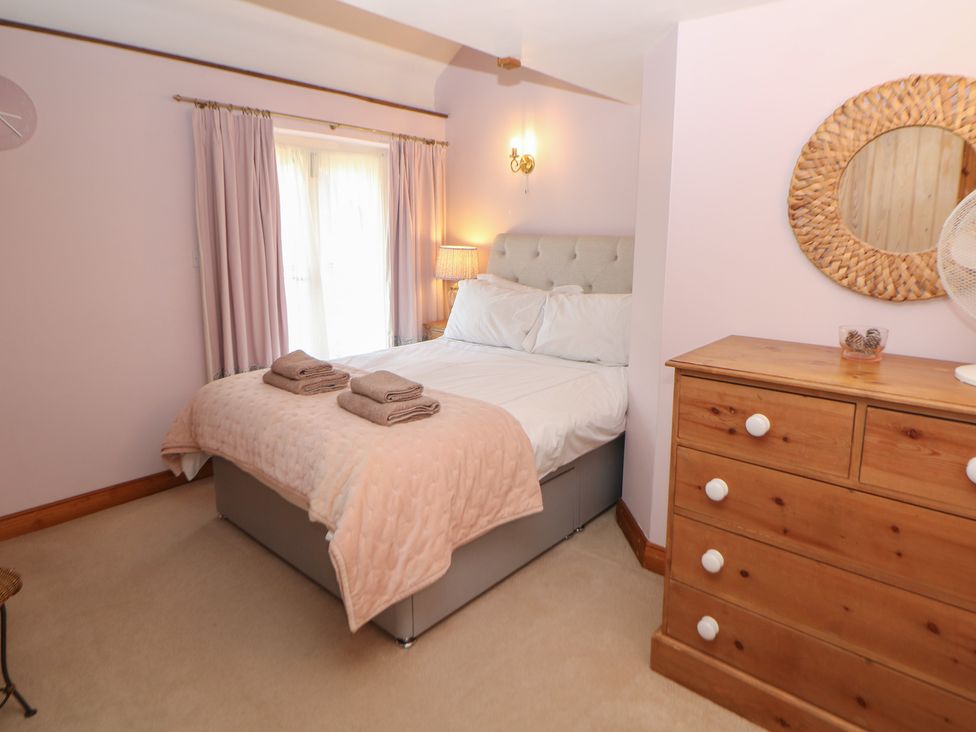 A bedroom with a bed, dresser, and curtains at Green Farm Stables in Hognaston near Carsington Water